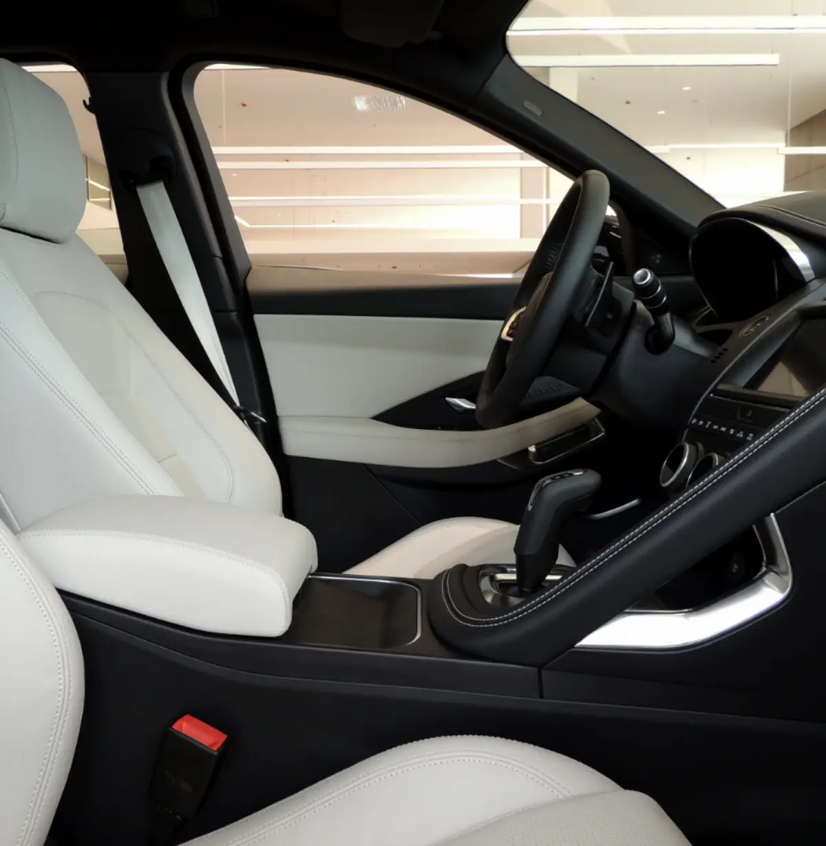 Interior view of a modern car with light-colored leather seats, a center console with gear shift, and a sleek dashboard featuring a large touchscreen display, steering wheel, and minimalistic design elements.